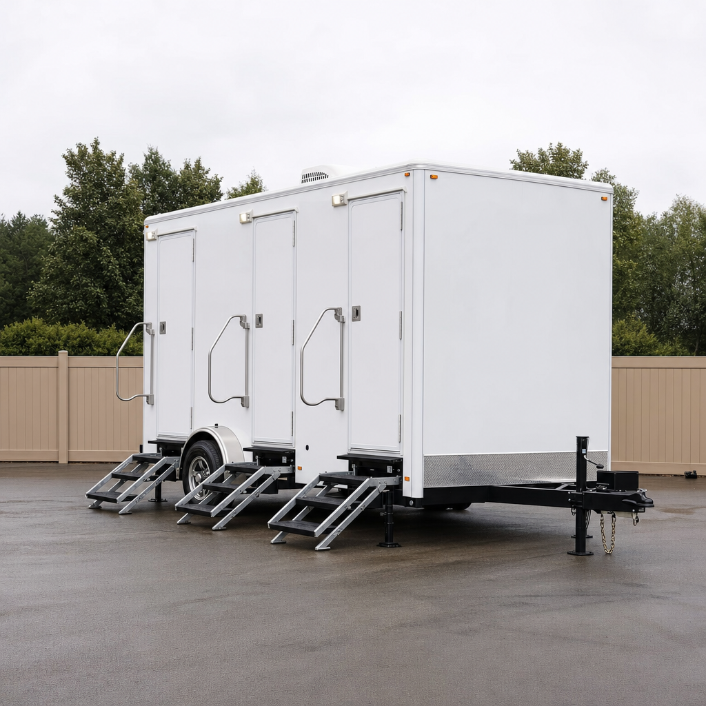 A clean white coach-style restroom trailer staged and leveled at a dispatch yard, ready for delivery